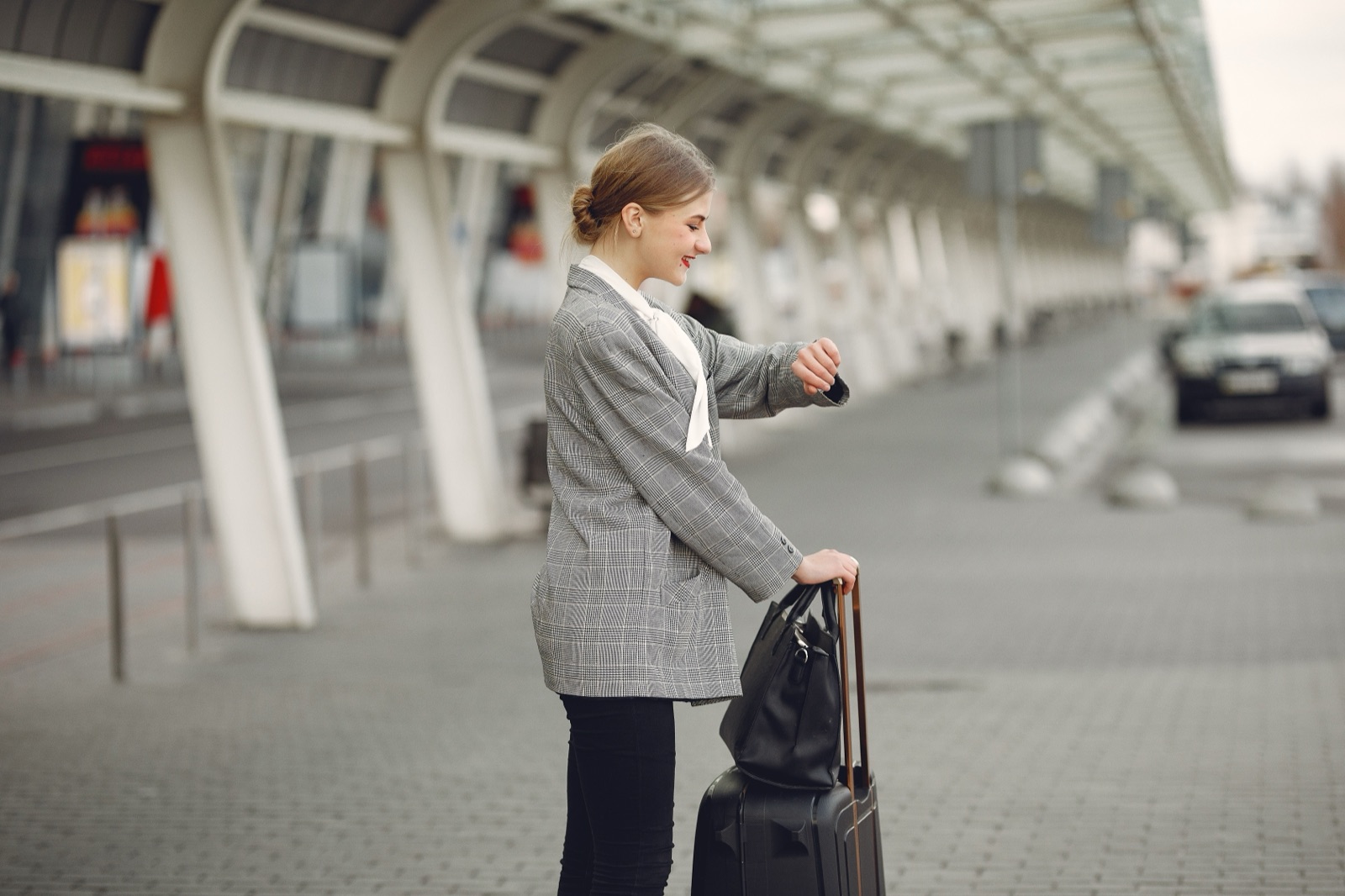 Passenger with luggage waiting for her London airport pickup chauffeur to arrive
