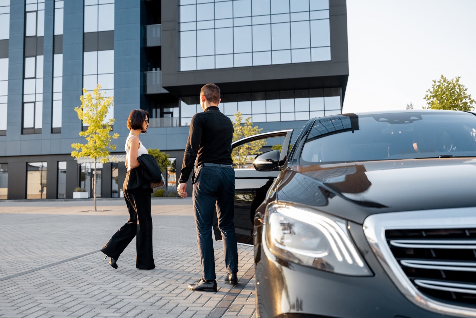 Chauffeur opening the car door for passengers arriving in Central London from Heathrow Airport