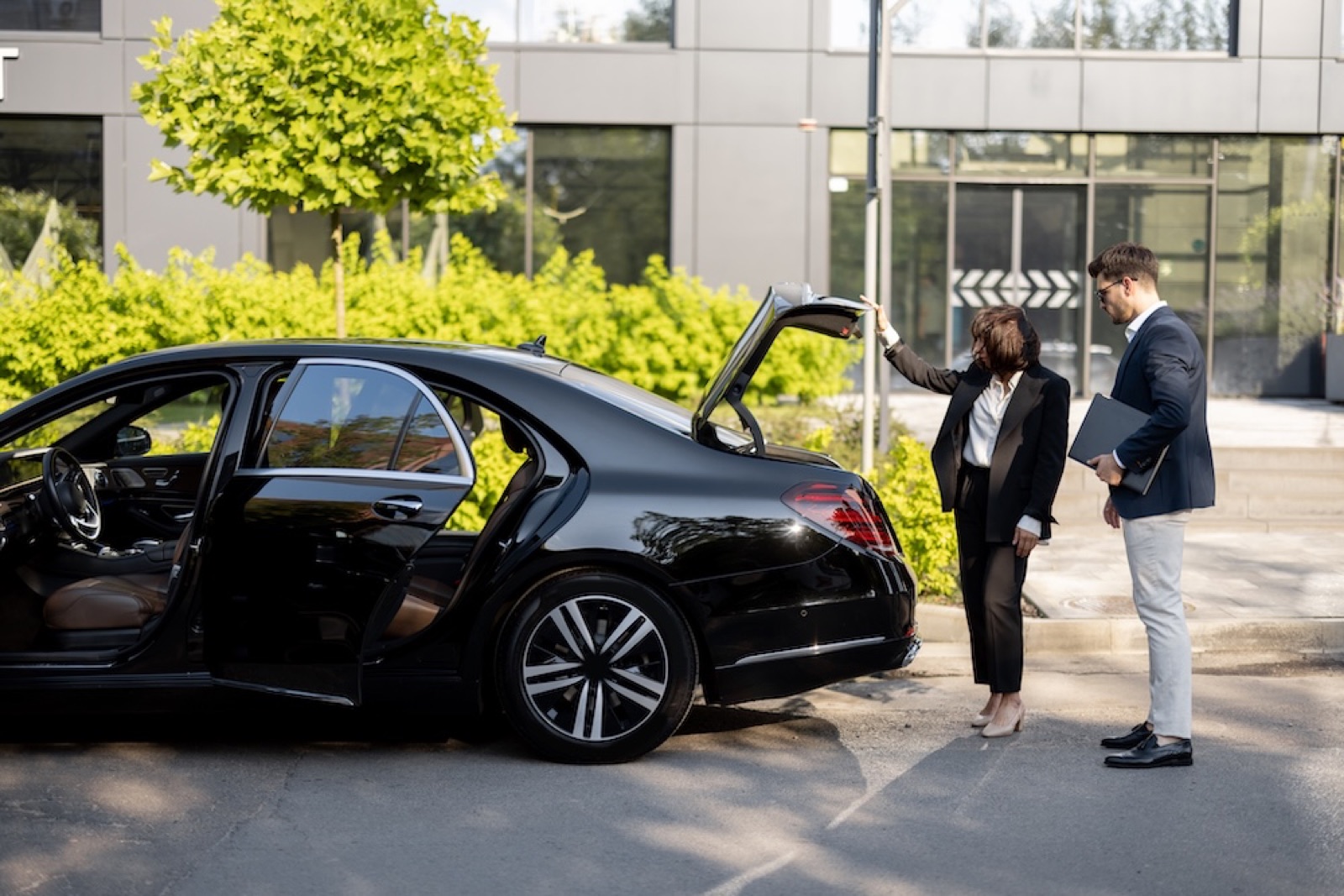 Business colleagues loading luggage into a private chauffeur car for a business trip