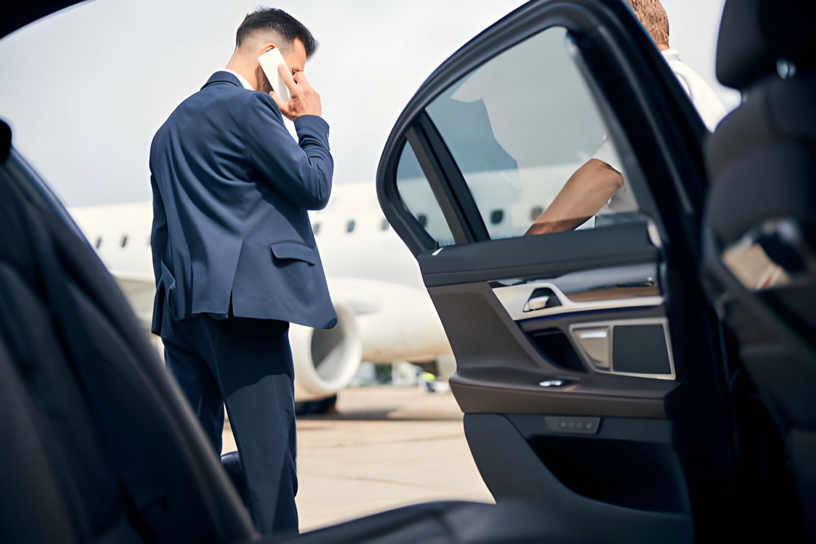 Chauffeur car waiting on the tarmac beside a private jet for a VIP airport transfer