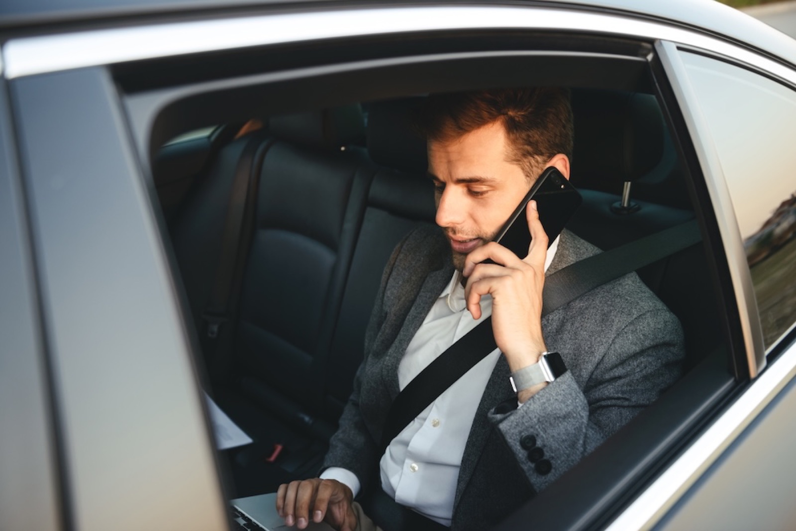 Executive taking a business call while travelling in a chauffeur-driven car
